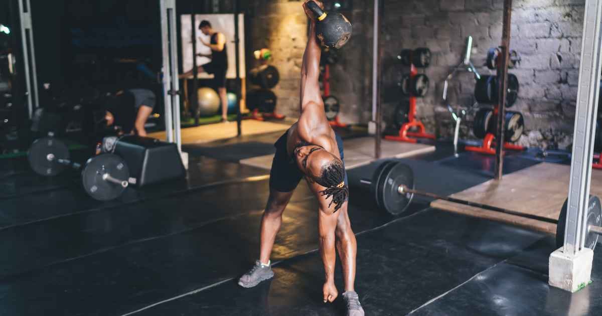 man doing kettlebell windmill exercise in the gym