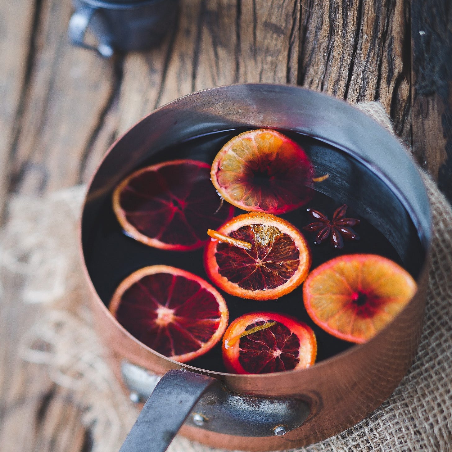 A pan of wine mulling with spices and slices of orange.