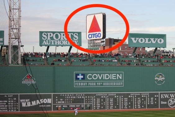 It’s a picture from inside Fenway Park, lookin’ out at that big green wall, I think they call it the “Green Monster”, an’ above it is towerin’ a big stinkin’ sign that says CITGO on it an’ has a big red triangle logo.