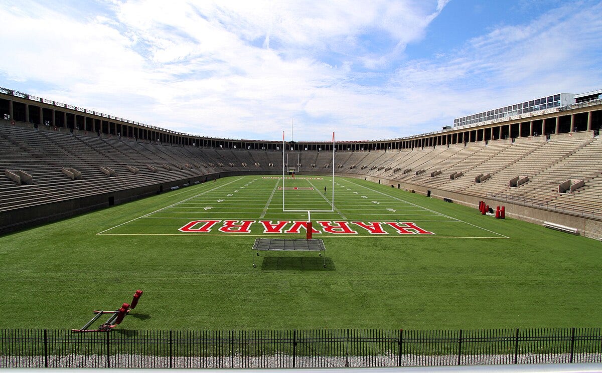 A football stadium viewed from behind the goal posts, with "HARVARD" written in the endzone