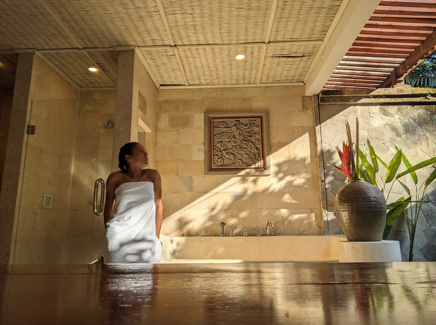 Nathalie sits on the edge of a bathtub with the sun hitting the marble.