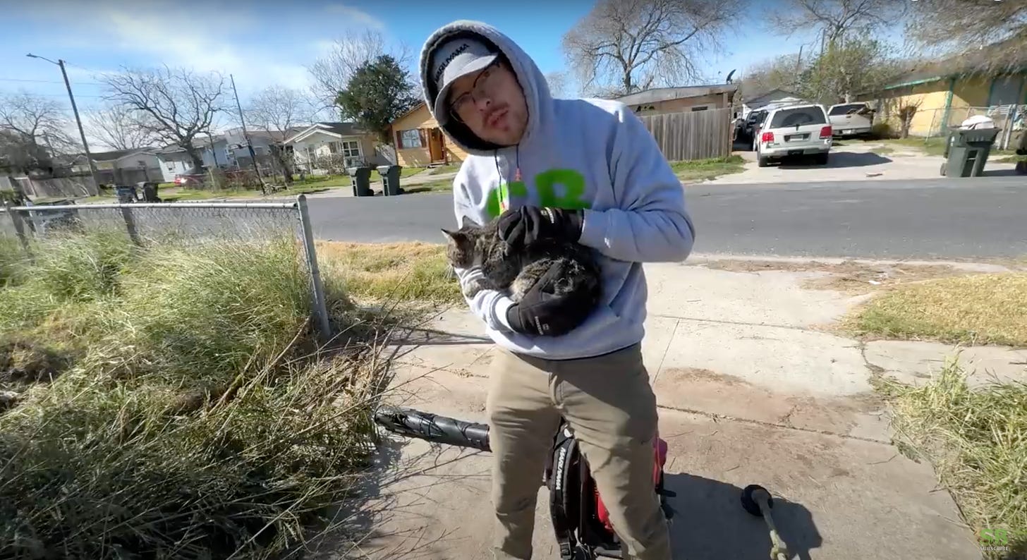 Spencer B. holds cat on the driveway of a yard he is transforming.