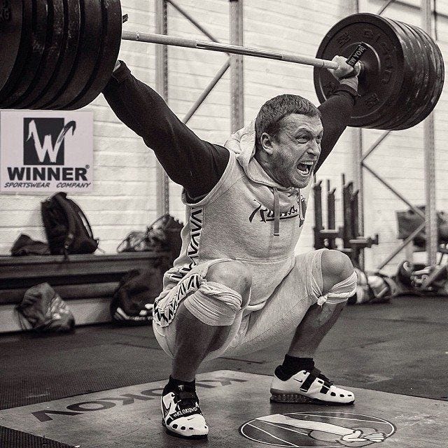 This may contain: a man squatting down while lifting a barbell