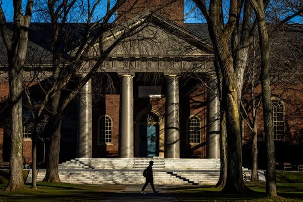 A person in shadow walks the Harvard University campus at end of day