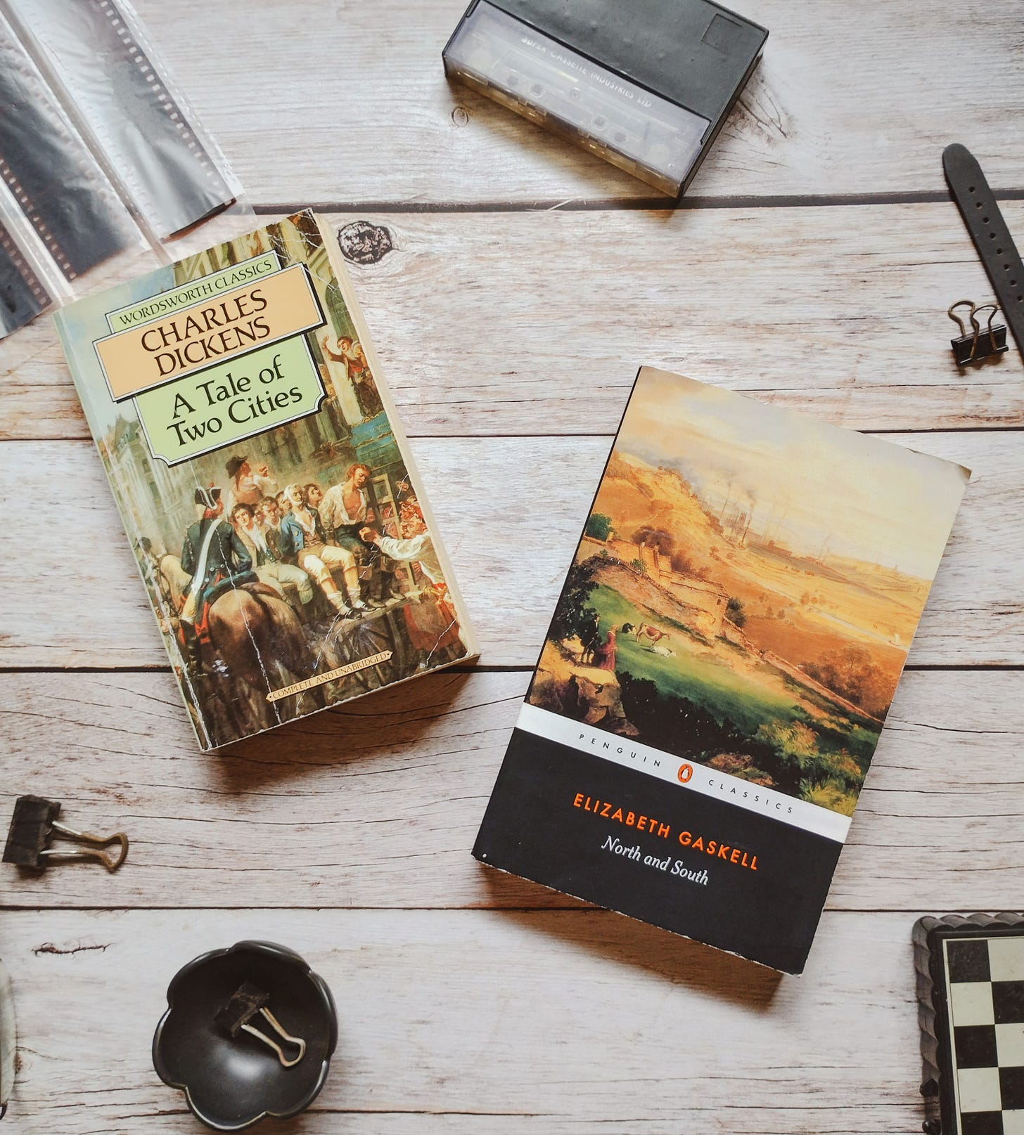 Two books on a wooden tabletop, Charles Dickens' A Tale of Two Cities and Elizabeth Gaskell's North and South