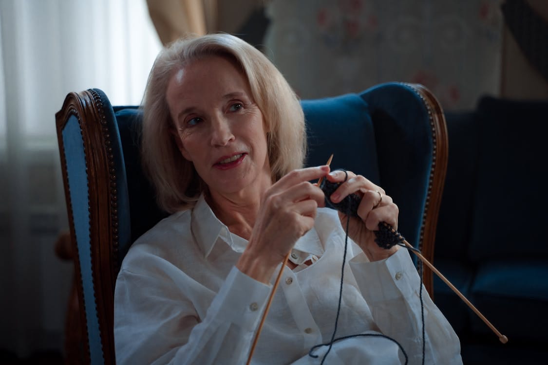 Free A senior woman enjoys knitting in a comfortable chair, creating a warm and cozy atmosphere indoors. Stock Photo