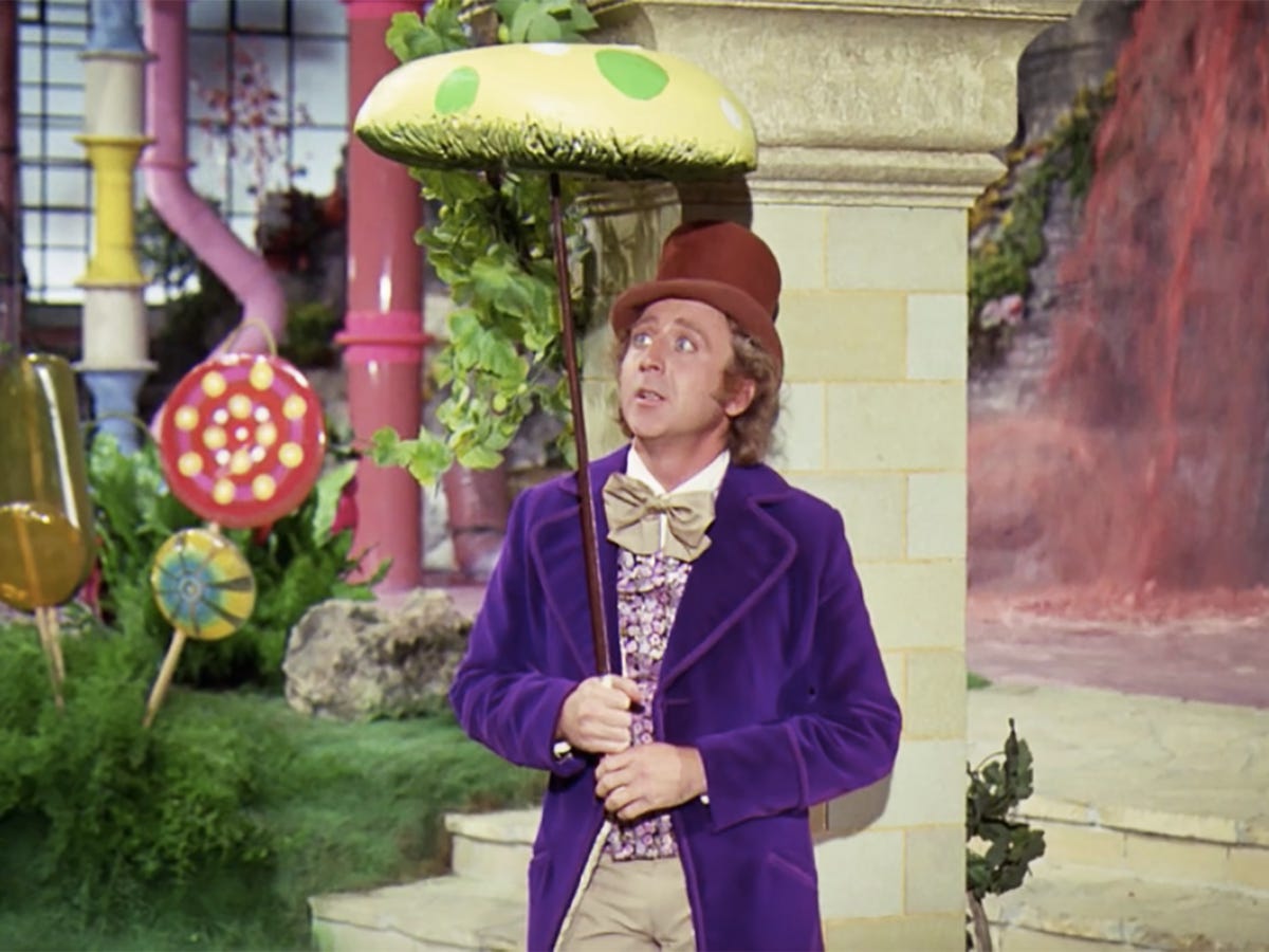 Gene Wilder as Willy Wonka standing in the Chocolate room holding a mushroom umbrella thing