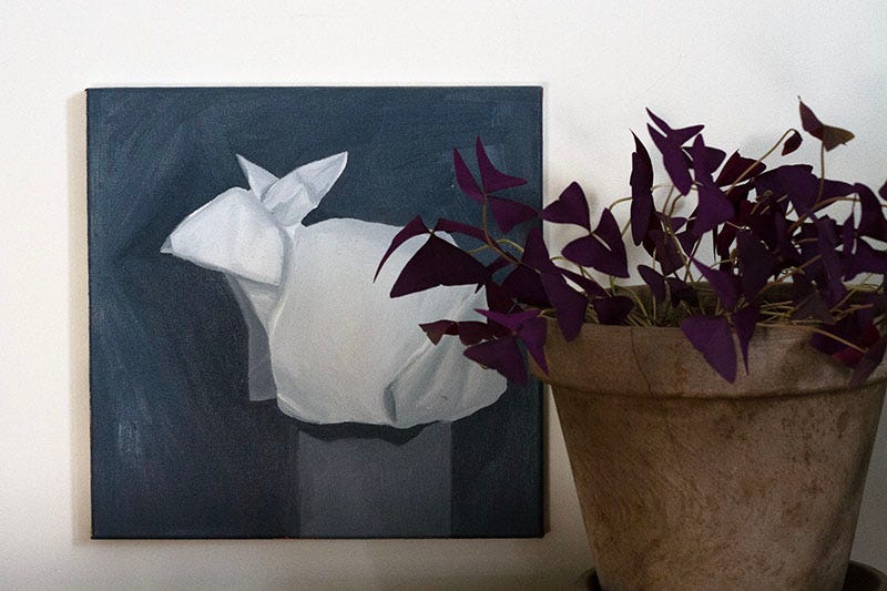 A black and white painting of an origami bunny next to a brown pot of purple oxalis. A black and white painting of an origami bunny next to a brown pot of purple oxalis.