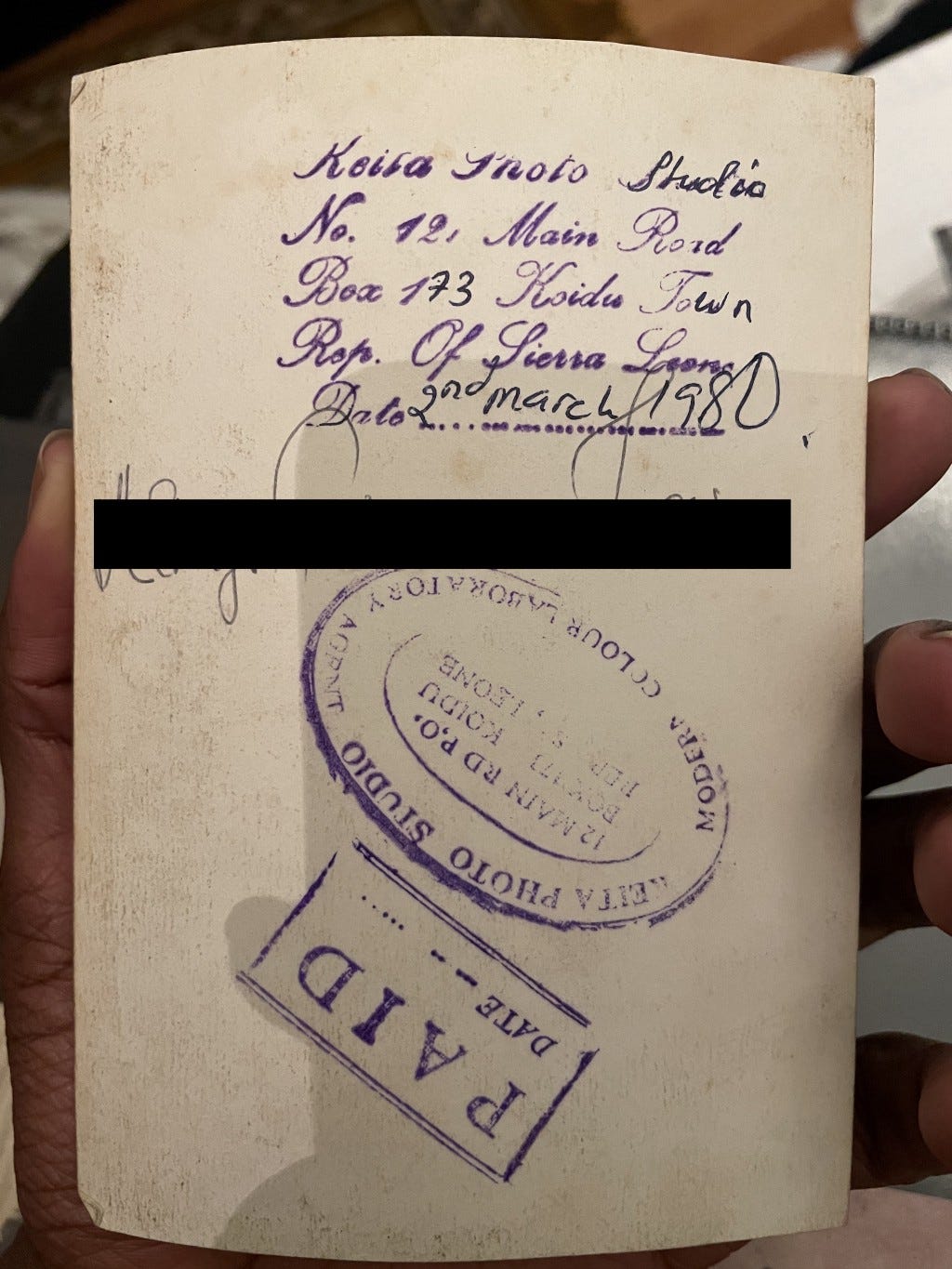 Back of aforementioned image, with stamps confirming the address of ‘Koidu Photo Studio’, date 2nd March 1980 and confirmation of payment. The name is blacked out for privacy.