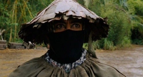 A screenshot from the film Tropic Thunder.  The character's costume of a Chinese farmer only shows his eyes.