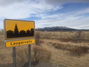 These signs indicate that you're entering into a town (with the town name below the cityscape). When you're leaving a town, you'll see the same sign with a line through the silhouette. 