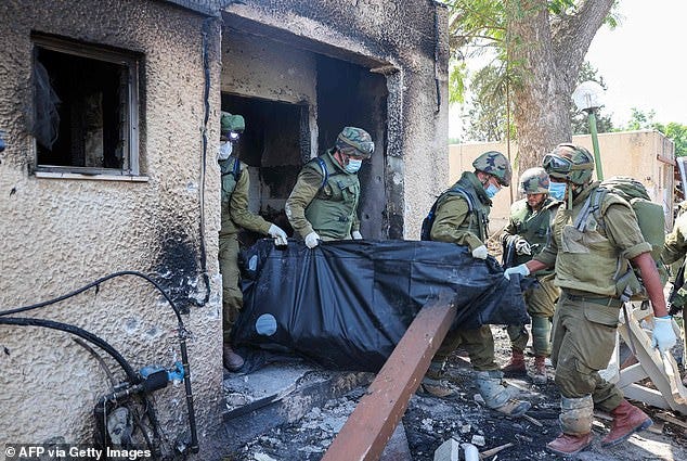 Israeli soldiers remove the body of a compatriot, killed during an attack by Hamas terrorists in Kfar Aza, on October 10