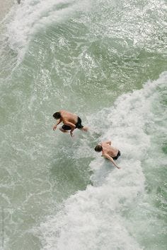 Two boys run and jump through the waves of Pensacola Beach as seen from above. #pensacolabeach #stockphoto #stocksy #florida