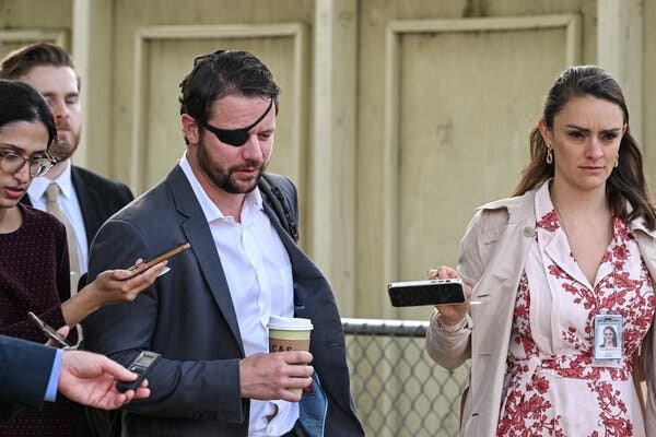 Representative Dan Crenshaw, wearing a gray blazer and an eye patch, talks to reporters as he walks outside the Capitol.