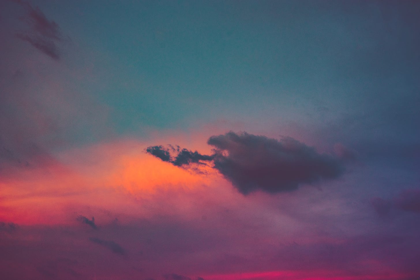 A vibrant sky with patches of orange, pink, blue, and violet. A small cloud with a smaller cloud-friend hangs in the middle of the image.