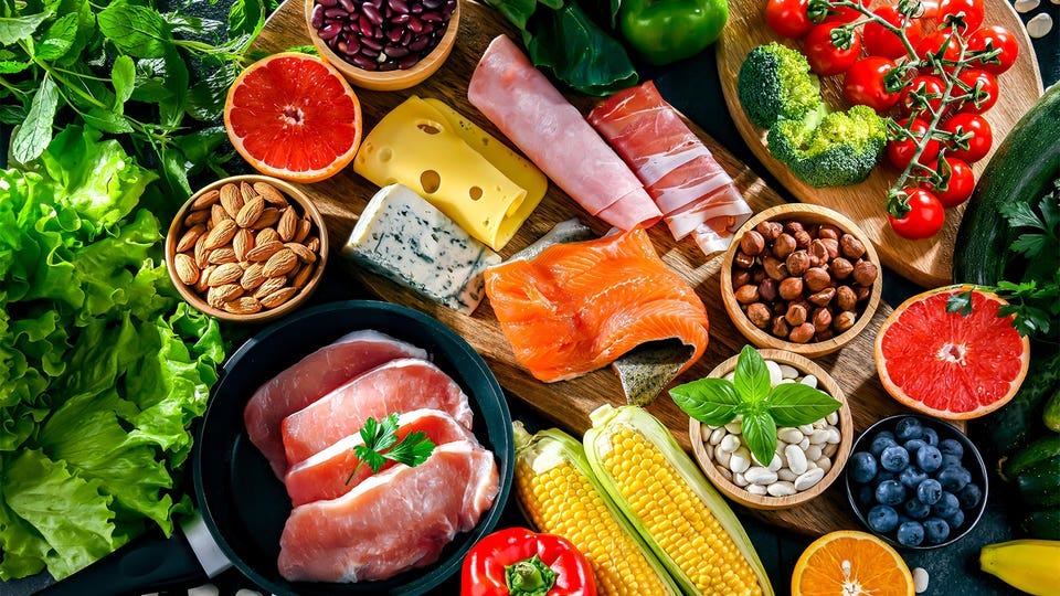 A photo of foods in a low-carbohydrate diet including, cheese, fish, corn, nuts, meats, vegetables, and fruit.