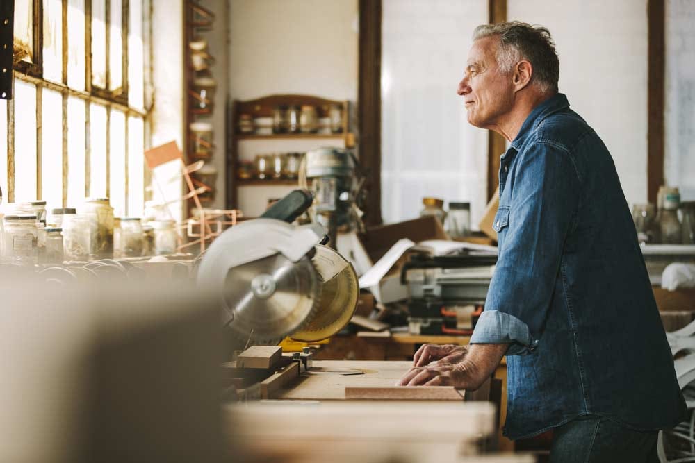 Thoughtful elder carpenter working in his workshop.