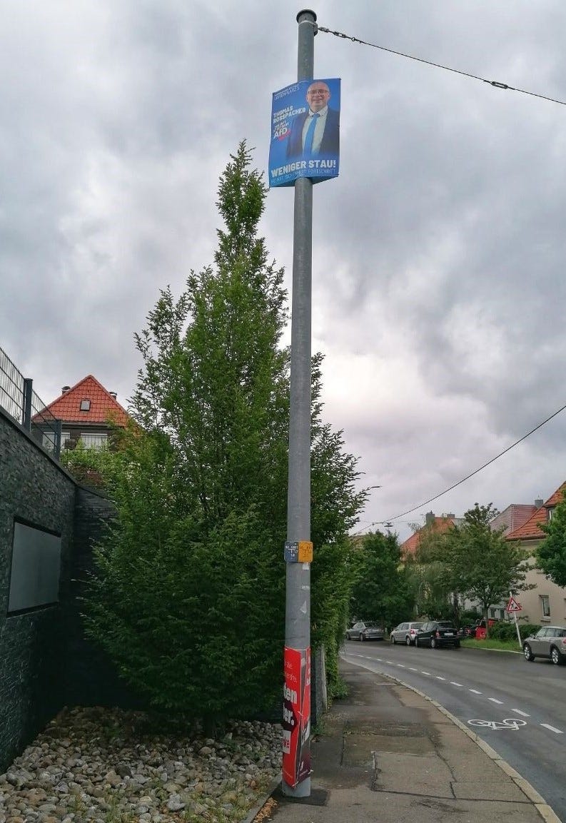 Quer stehendes Foto eines sehr hoch hängenden AfD-Wahlplakats an einem Straßenpfosten in Stuttgart.