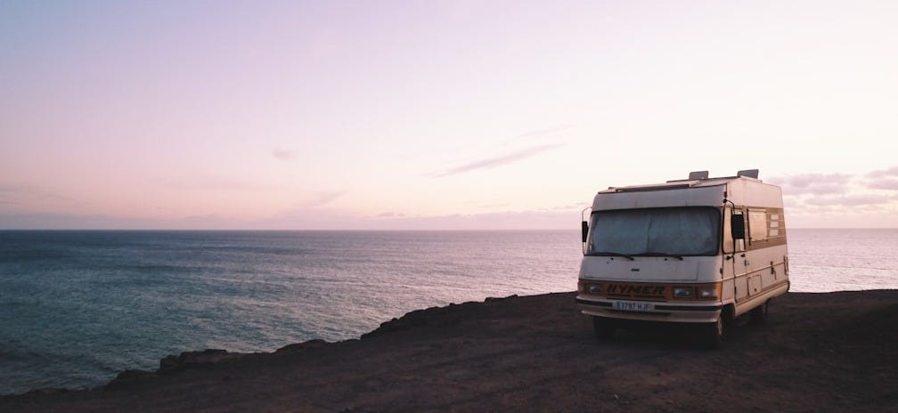 RV parked beside the edge of island during sunset