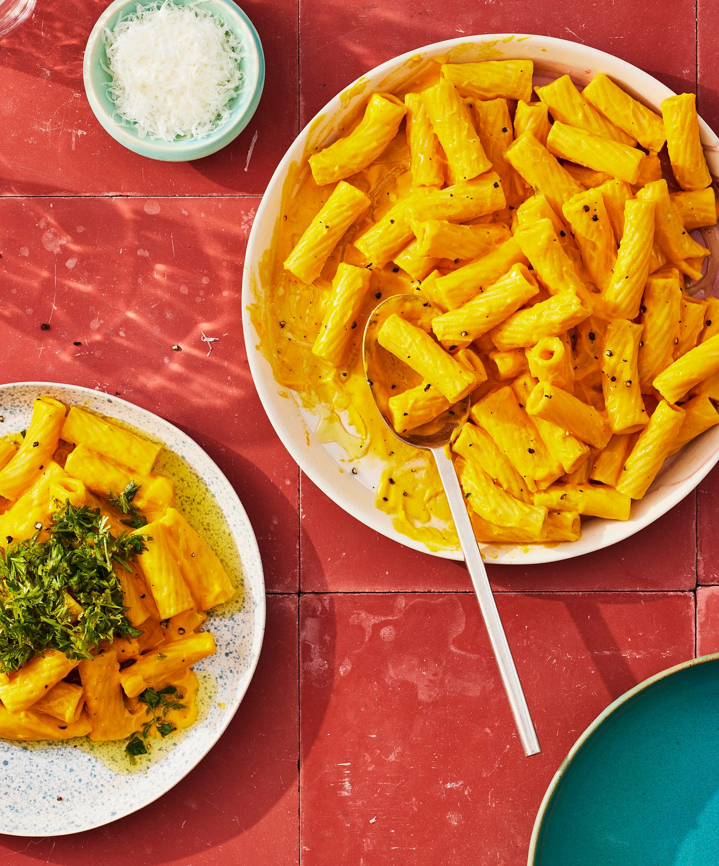 Serving plate and individual plate of creamy carrot rigatoni.