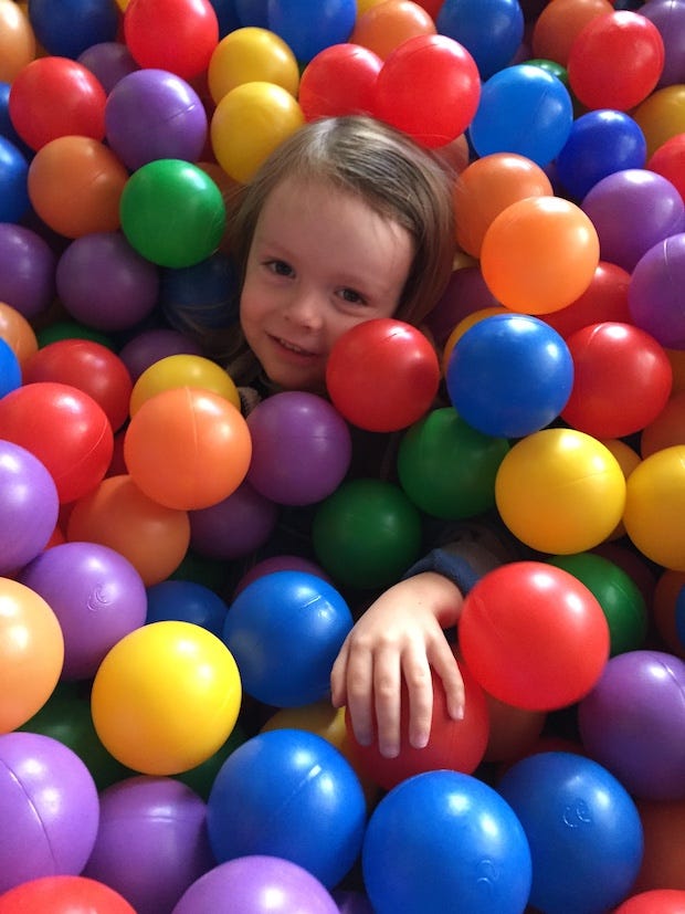 neurodivergent kid playing in a colorful ball pit