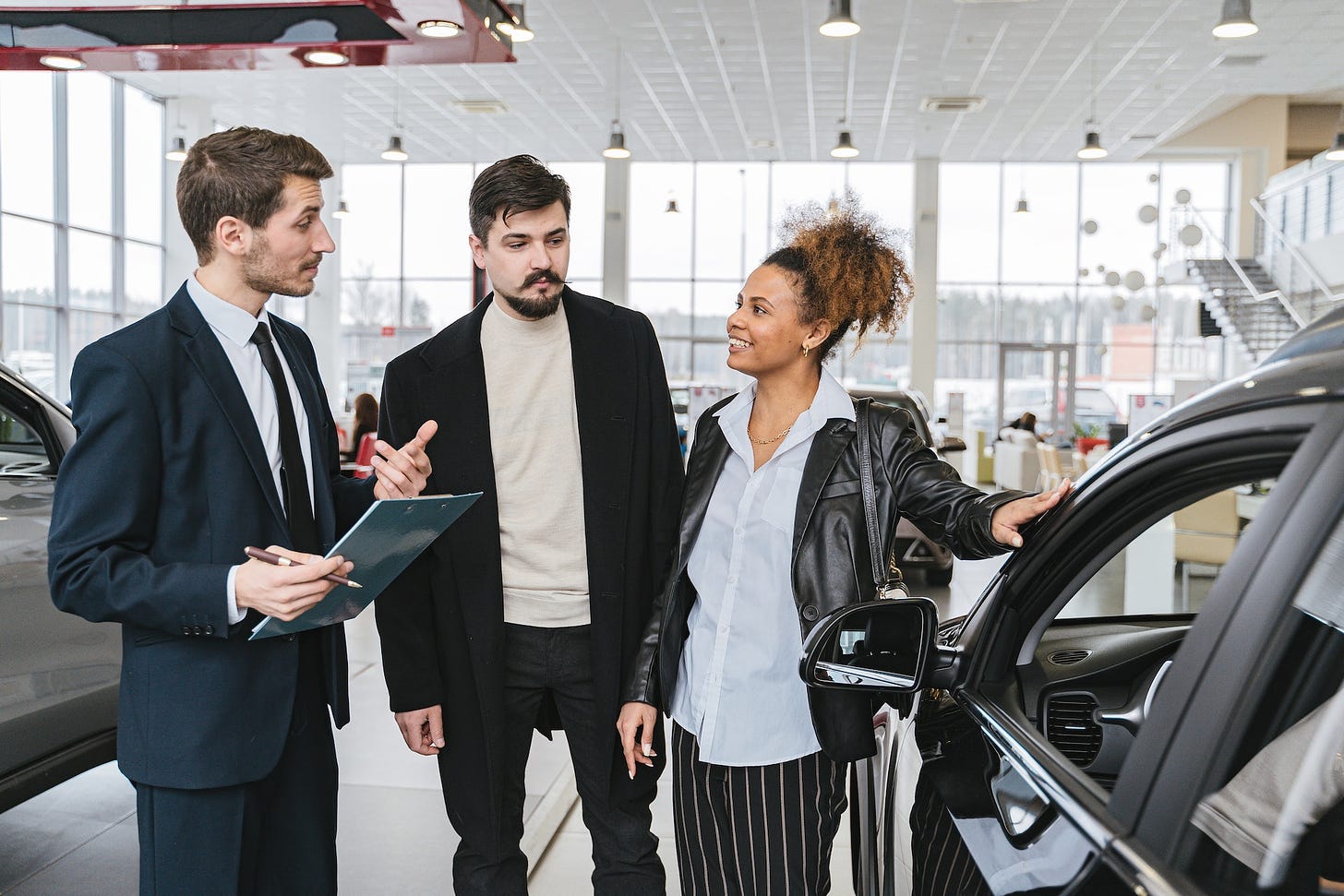 Man in blue suit talking to a woman at a car dealership