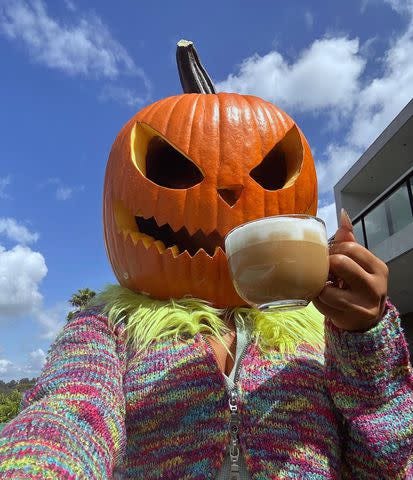 Picture of Megan Thee Stallion wearing a pumpkin head and drinking a latte