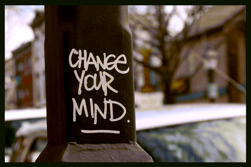 Streetlight post with while grafitti text: Change Your Mind