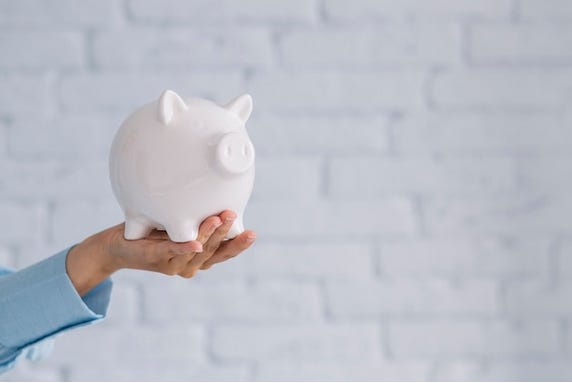 Free photo | businesswoman showing coins with white piggybank on desk