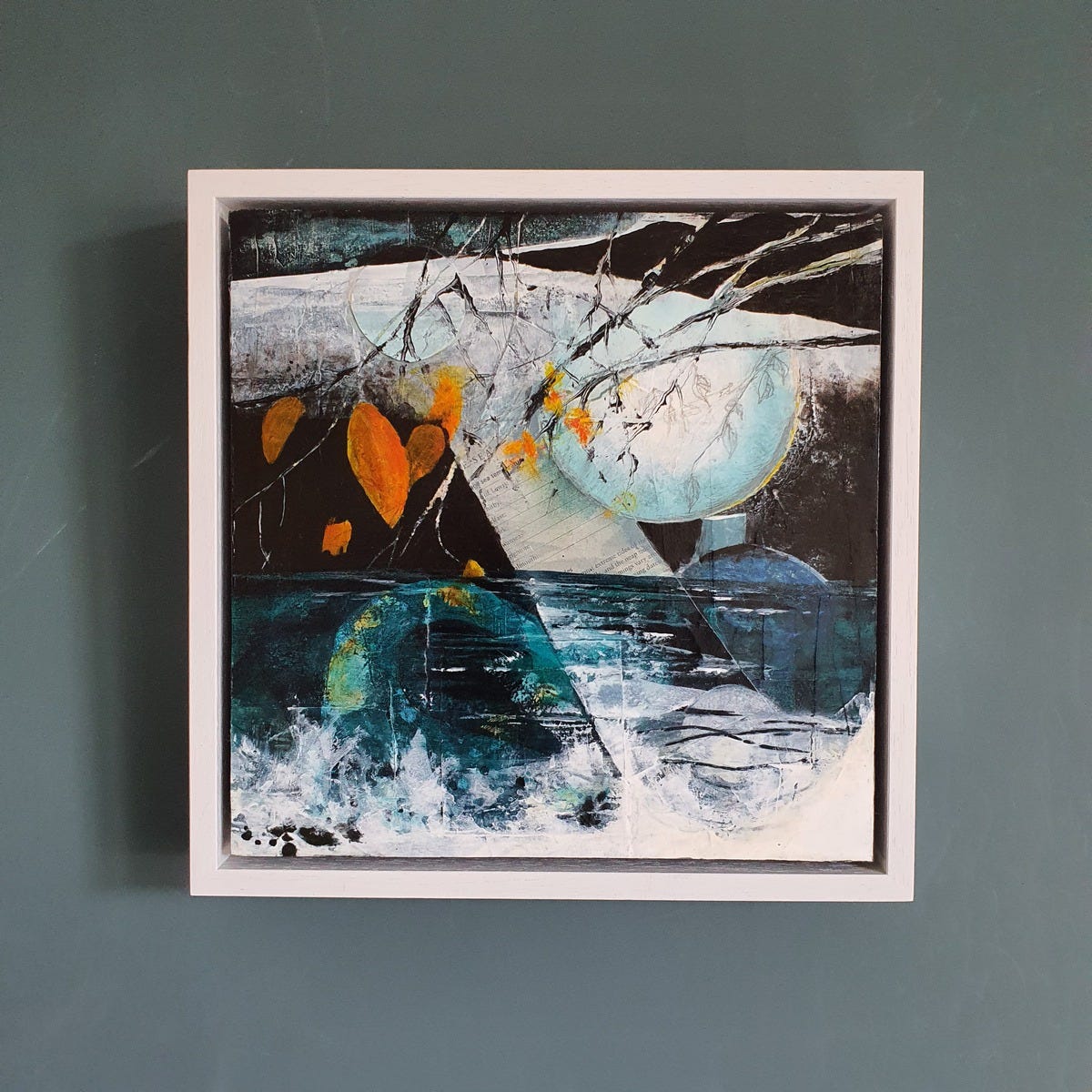 Rising on the wall framed in a white square tray frame. Rising is an abstract painting with a moon and water rising and a few orange leaves from a tree over the inky depths below