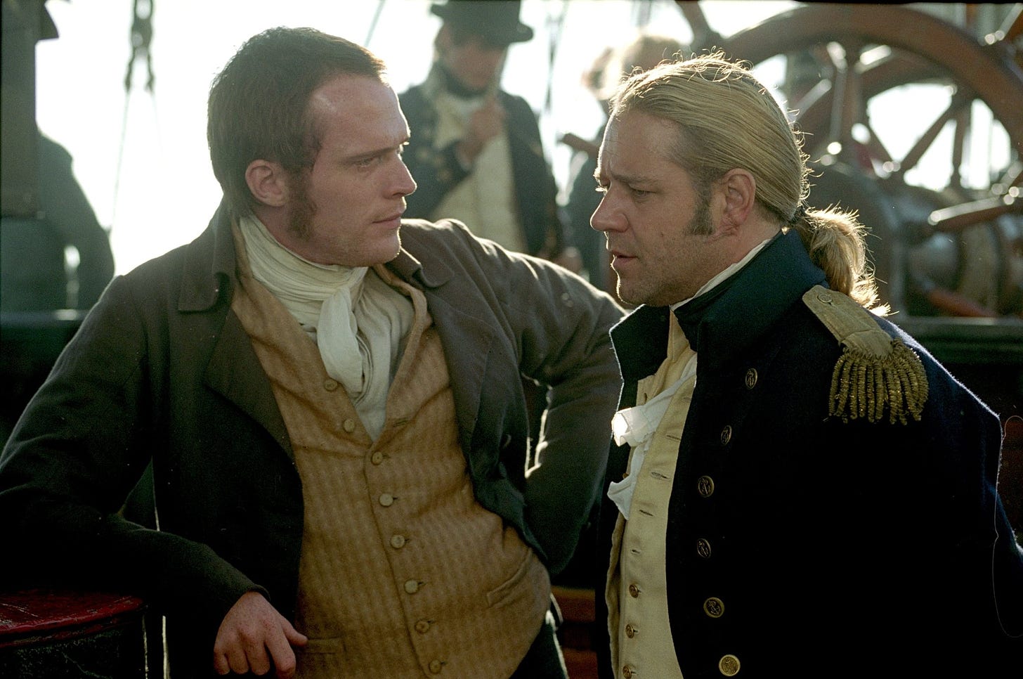 two men in napoleonic era clothes look at each other on a ship. 