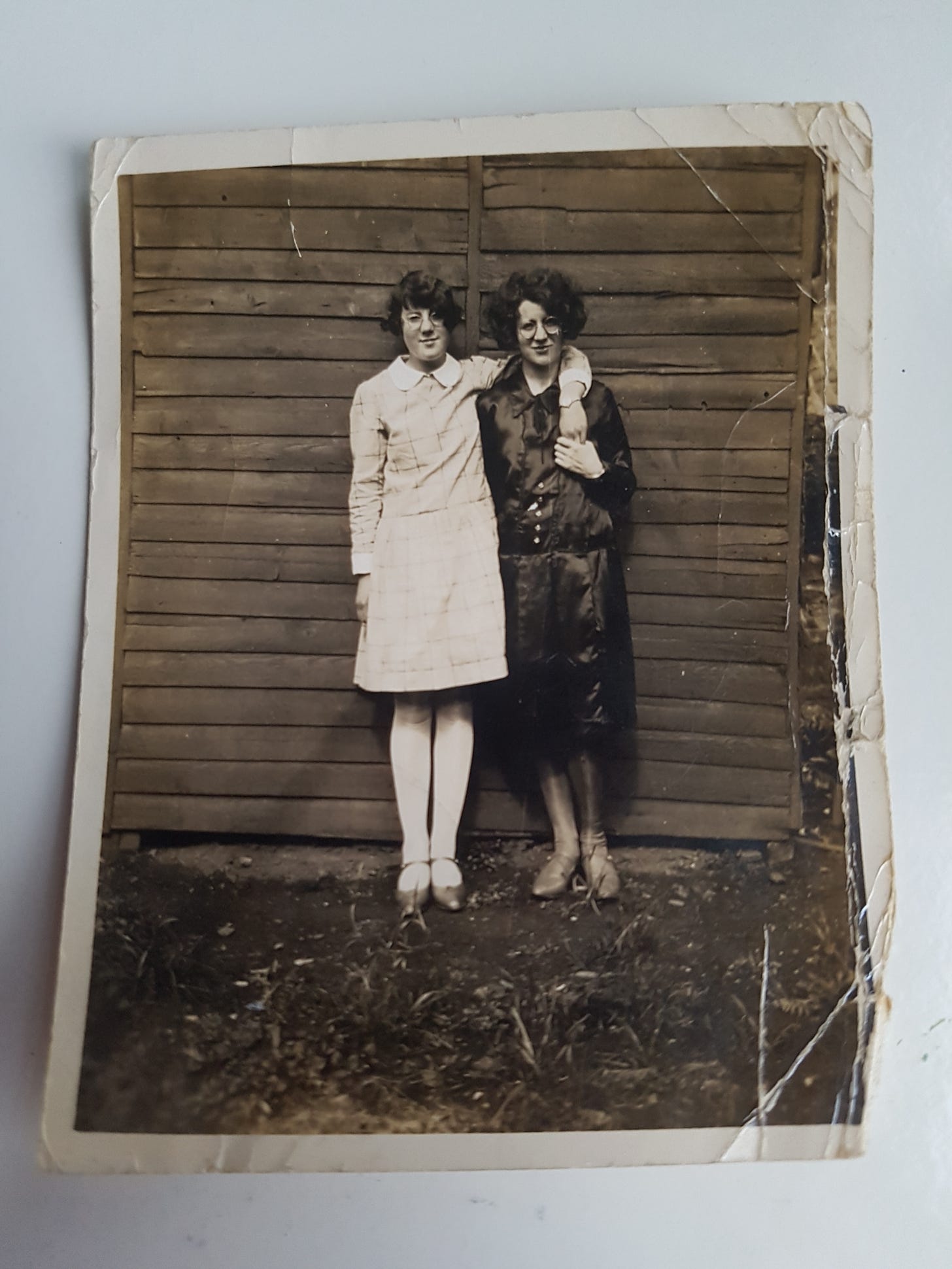 Two fashionable young ladies from Fife, wearing 1920s dresses and bobbed hair in a family photo, placed on a white desk.