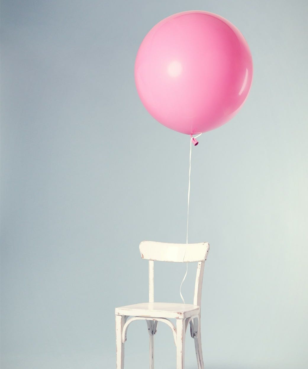 pink balloon tied on white wooden chair