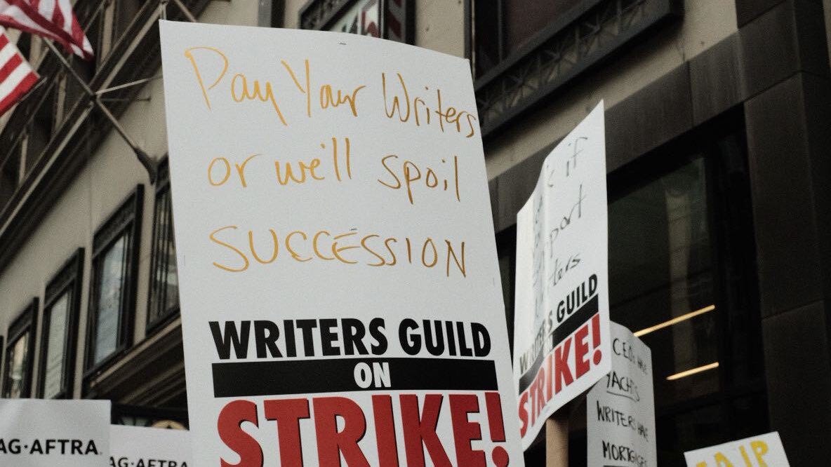 A picket sign that reads "pay your writer's or we'll spoil succession" (beneath it says "Writers Guild on Strike"