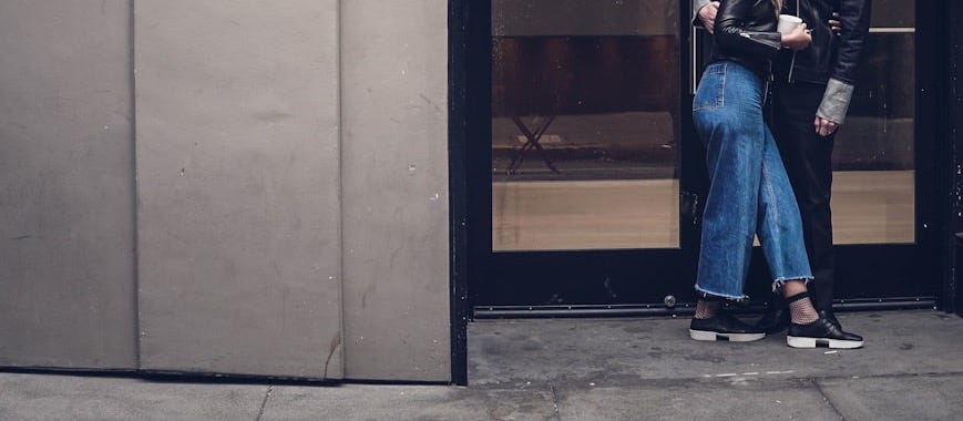 photo of man and woman kissing beside glass doors