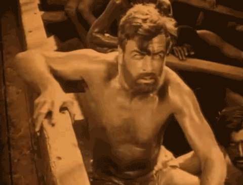 A galley slave, played by Milton Sills in 1924 film The Seahawek, wearing only a loin-cloth and chained to the bench - animated gif