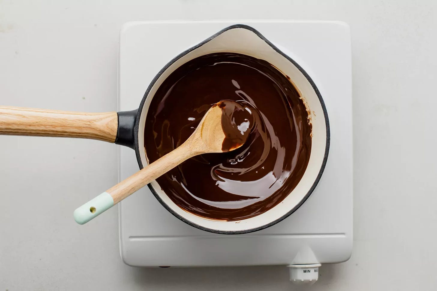 Melted butter and chocolate stirred together in a saucepan with a wooden spoon