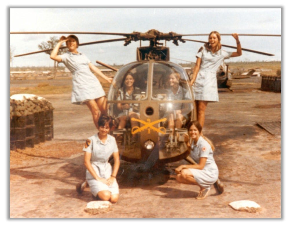 Donut Dollies pose around a military helicopter. They are smiling and having fun.