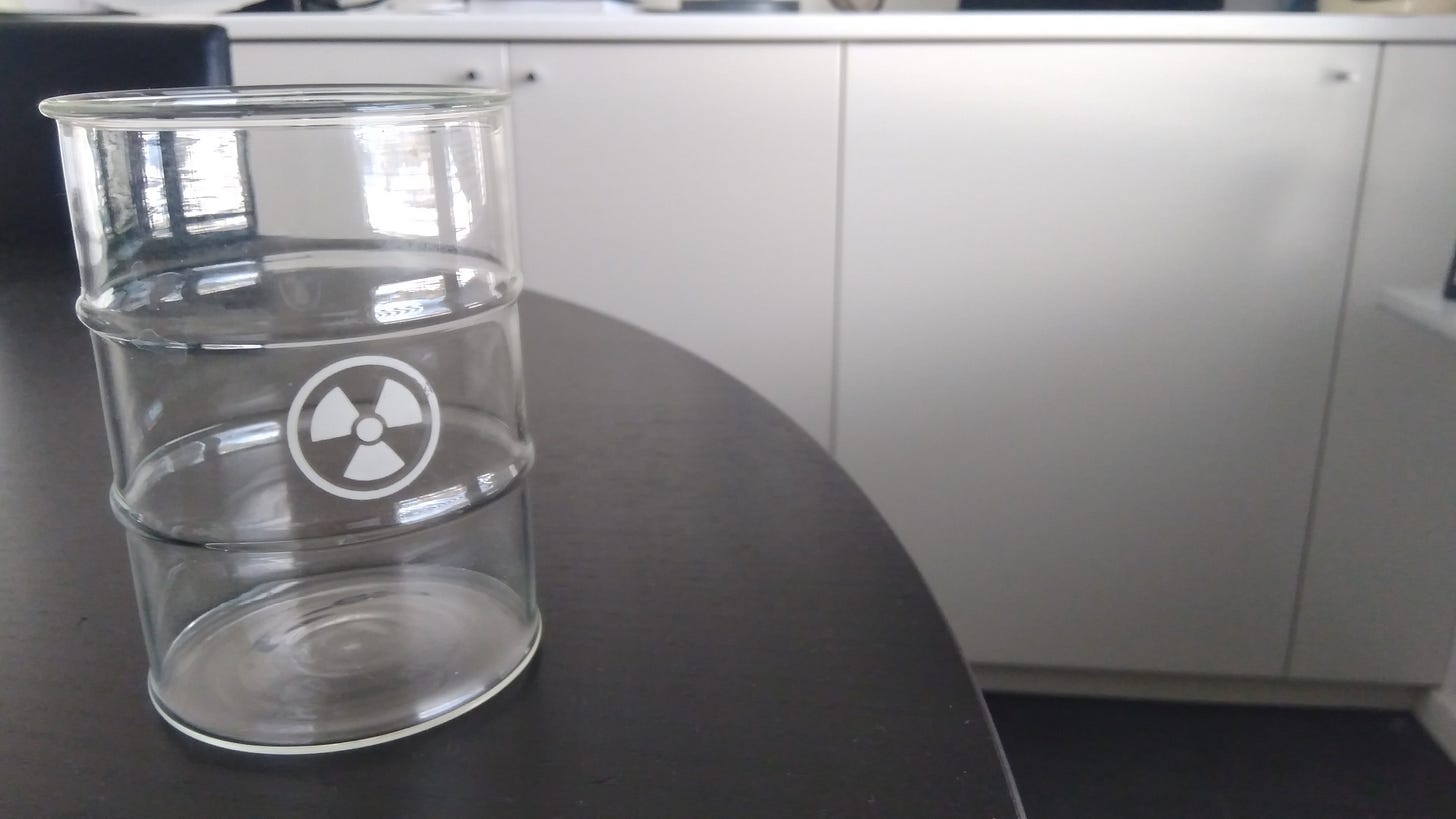 Clear beaker on a kitchen table with nuclear trefoil printed on the side