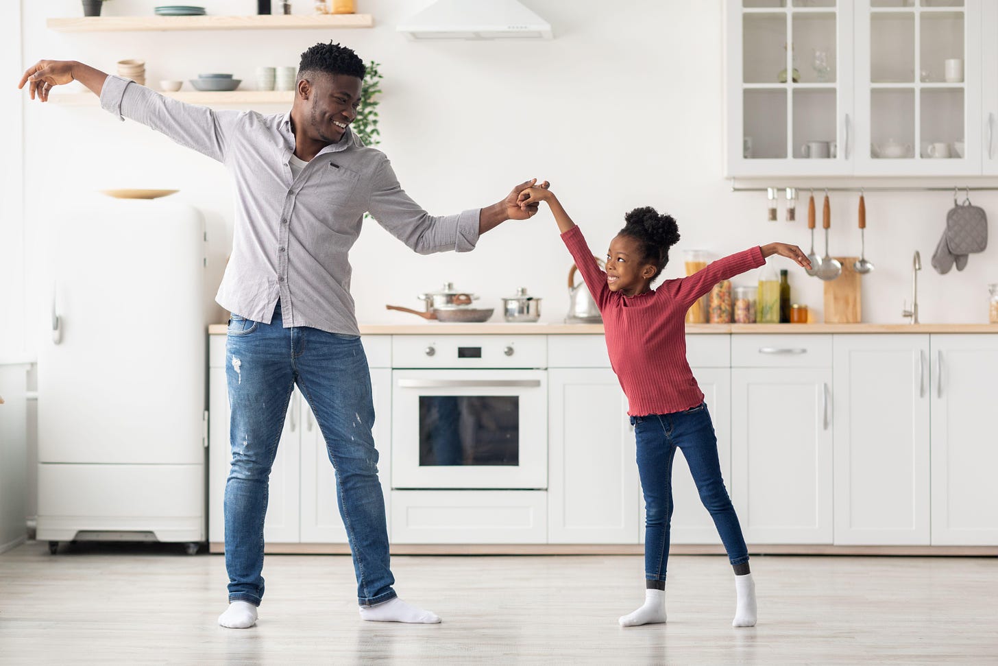 Cute black father and daughter dancing at kitchen