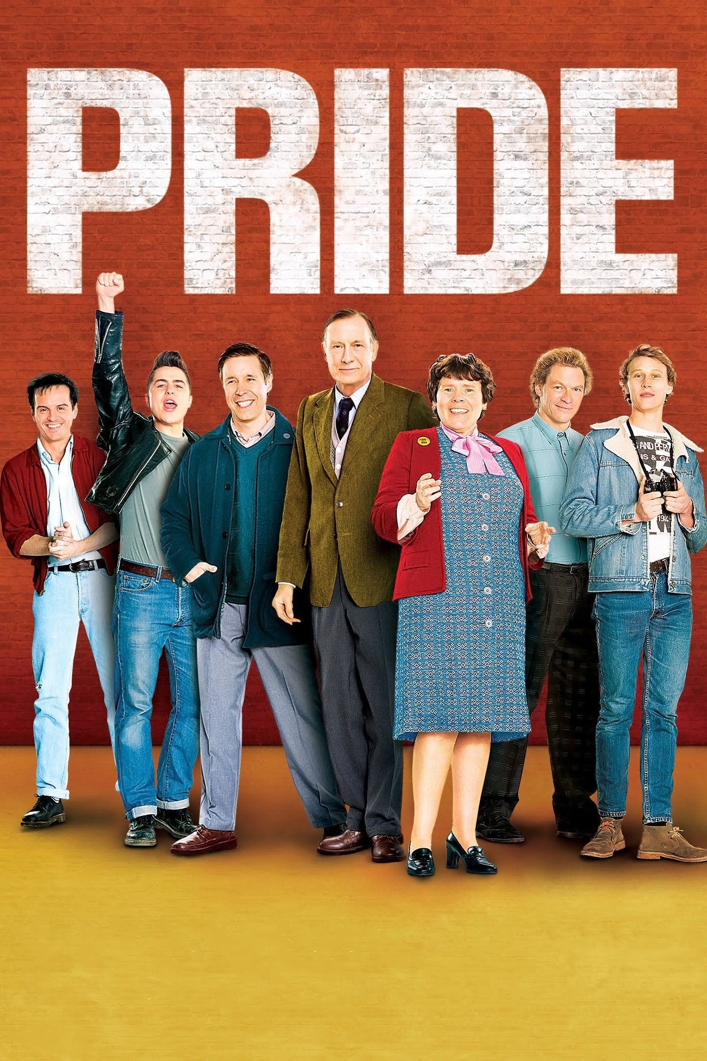 Movie promo image for Pride, which shows the title in white paint on a brick wall with a bunch of the all white cast beneath it. 