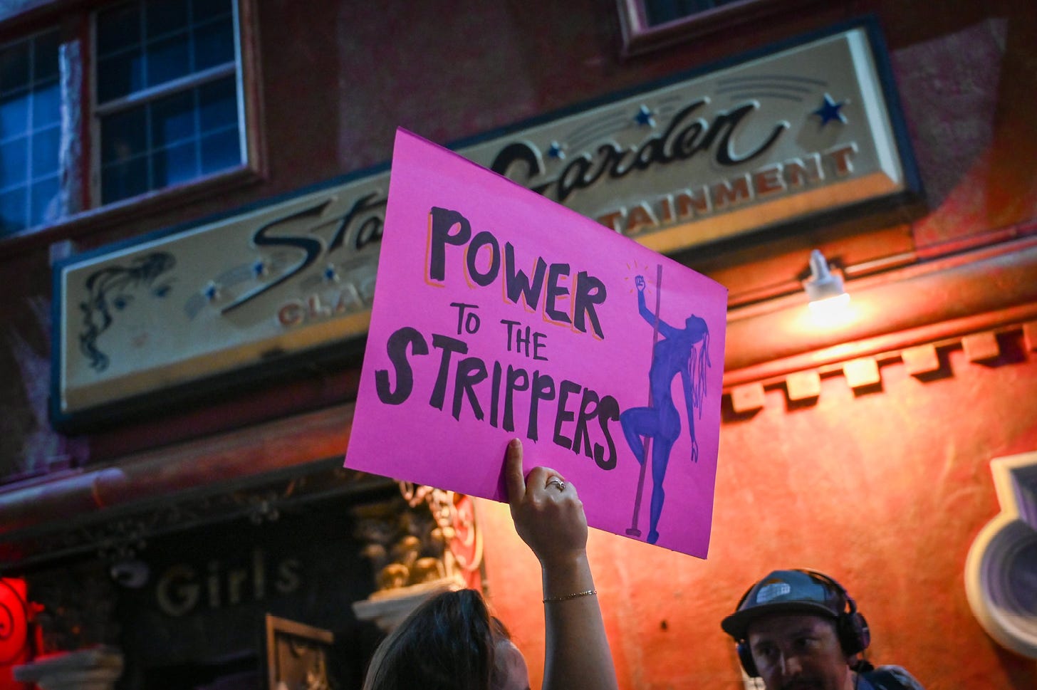 Sign that reads power to the strippers with the Star Garden sign behind it 