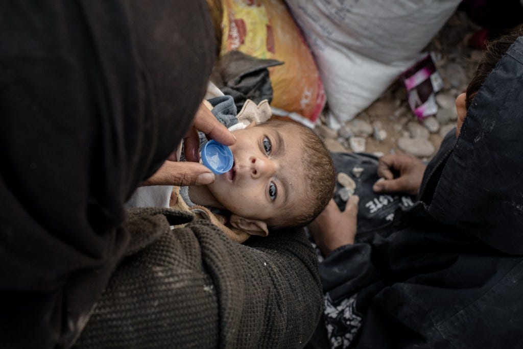 A woman gives her young child water while waiting to be let into the Hasansham camp for displaced persons on Nov. 4, 2016.