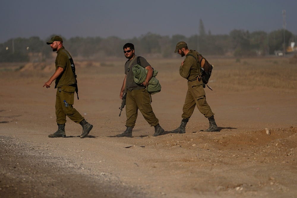 Israeli soldiers walk through a staging area for tanks near the Gaza border on May 24, 2024. (AP)