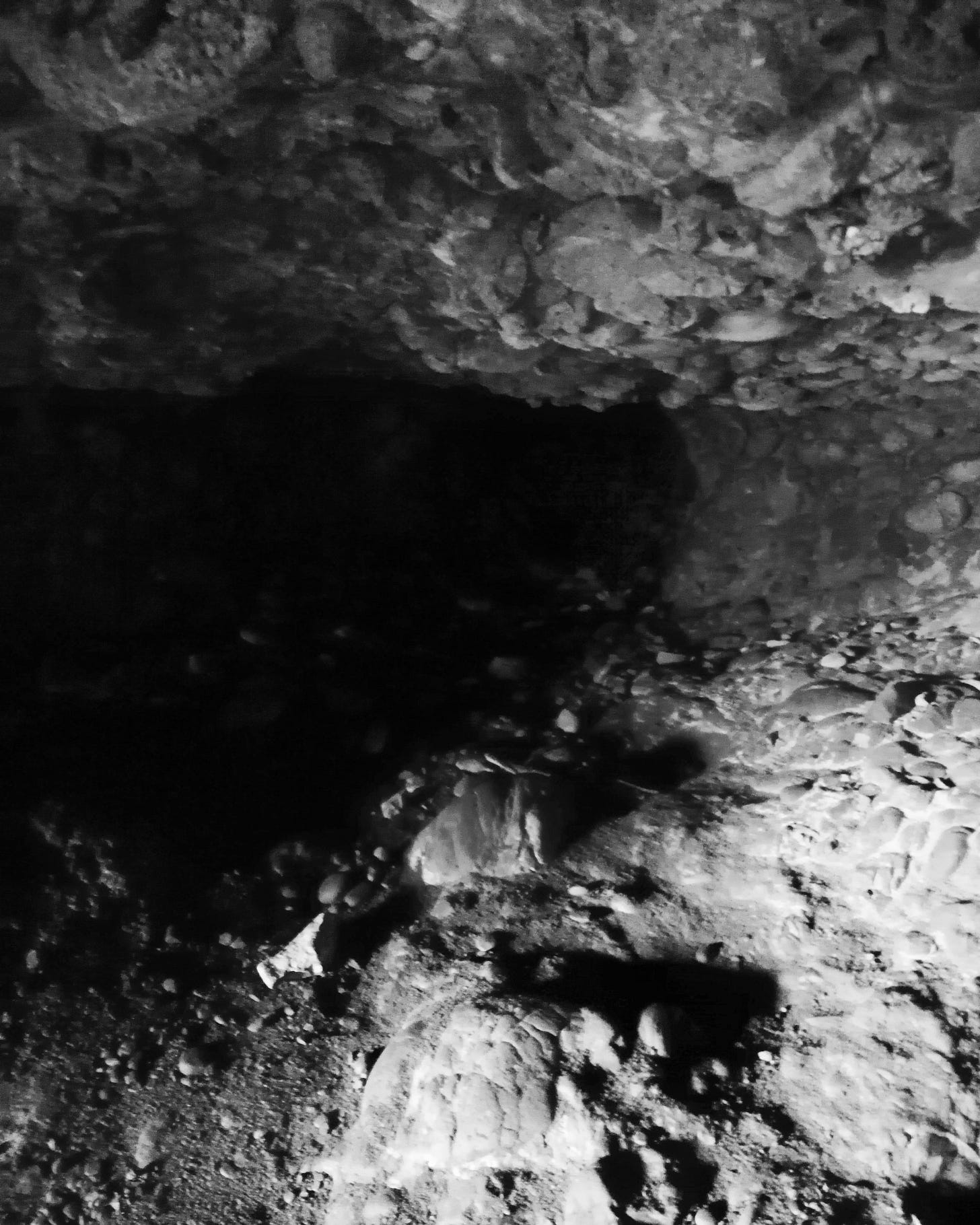 A black and white image of a the inside of a small cave