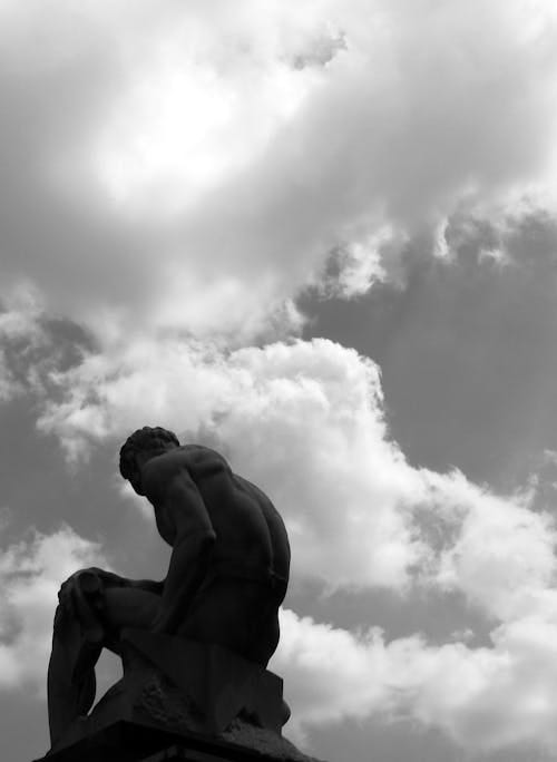 Free Grayscale Photo of Man Statue Under Cloudy Sky Stock Photo