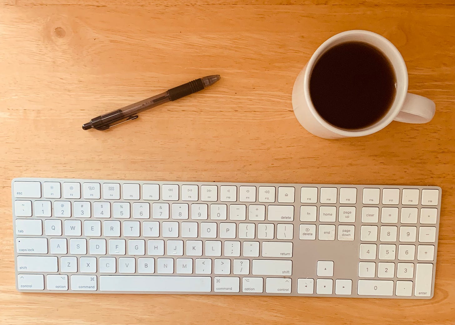 keyboard, pen, coffee on a wood table