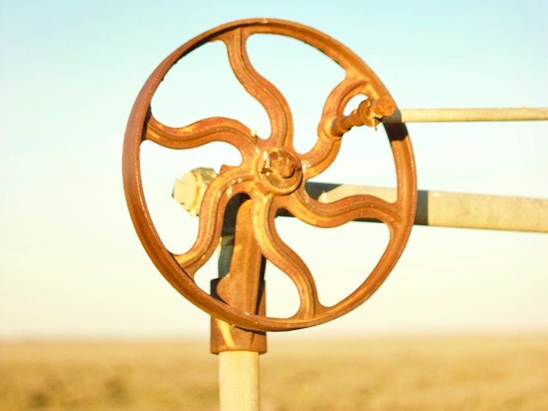 a wooden wheel on a pole in the middle of a field a wooden wheel on a pole in the middle of a field