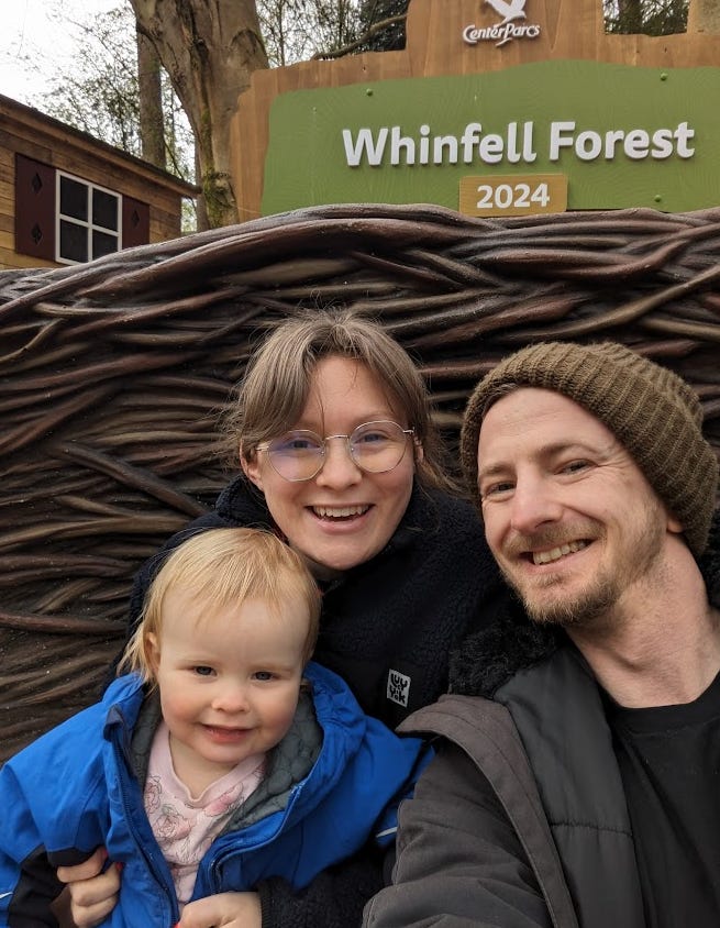 Ellen, Craig and Miri (toddler) taking a selfie in front of the Whinfell Forrest sign at Center Parcs.