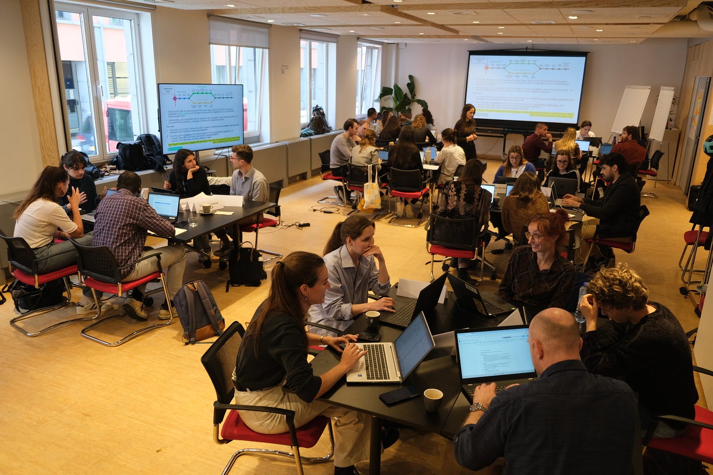 Groups of people around tables discussing something in a workshop-style event